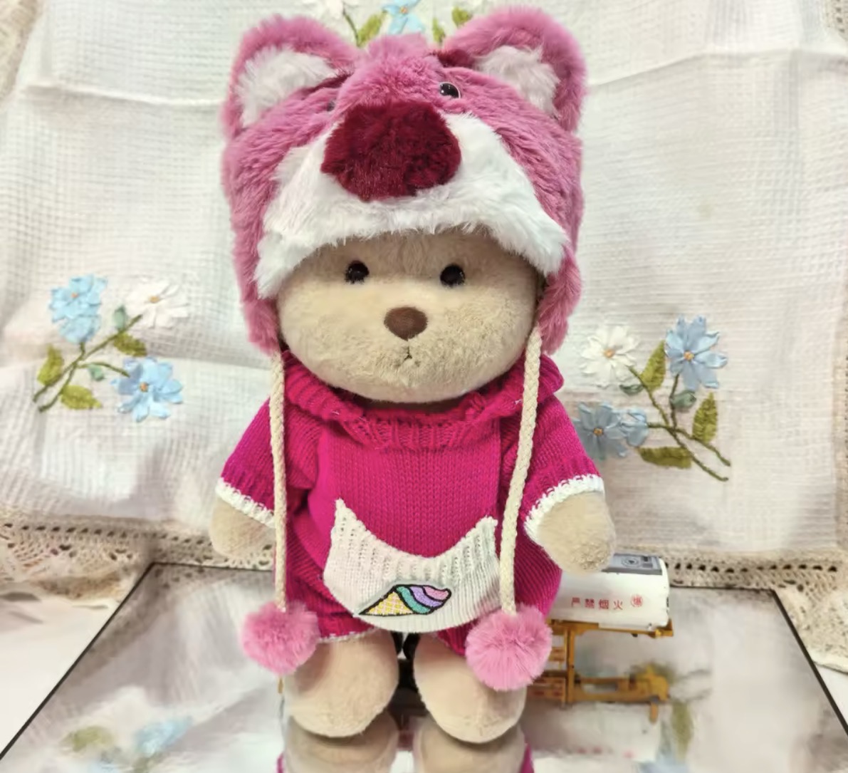 Adorable teddy bear wearing a cute pink fox hoodie and knit sweater